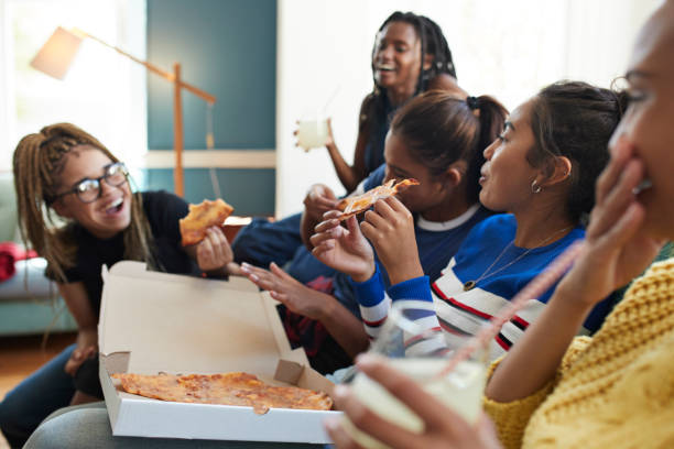 cheerful young women eating fresh pizza - junk food stock pictures, royalty-free photos & images