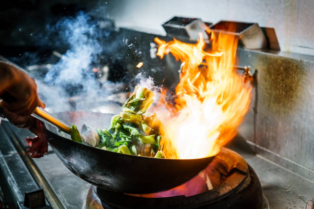 chef in restaurant kitchen at stove with high burning flames - food stock pictures, royalty-free photos & images