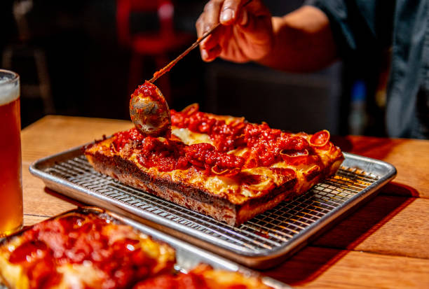 Chef Michael Chambers, in typical Detroit fashion, sauces the top of a Detroit original pepperoni pizza at Red Light photographed for Weekend in...