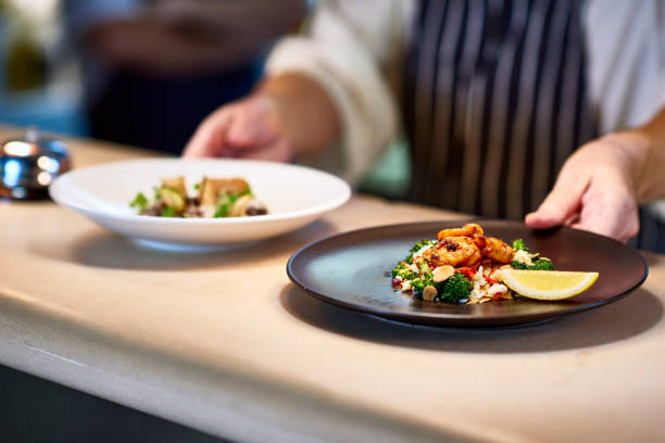 chef placing dishes of prepared food on counter - food stock pictures, royalty-free photos & images