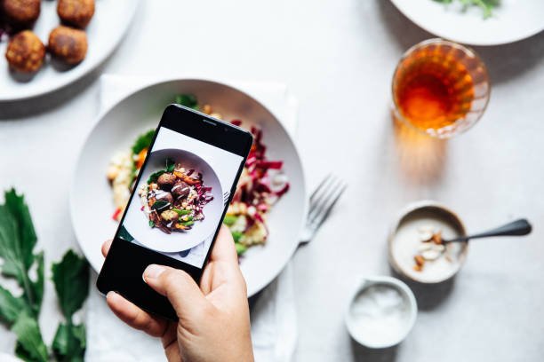 chef taking photograph of vegan falafel bowl on table. - food stock pictures, royalty-free photos & images