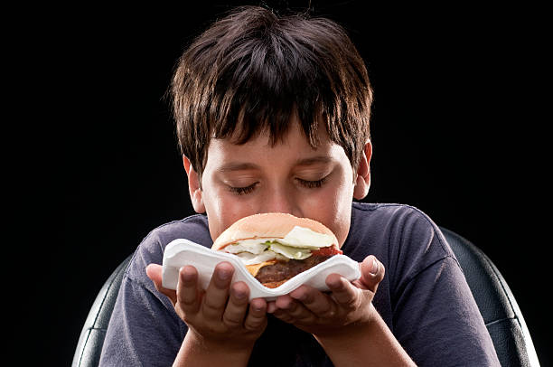 child smelling a hamburger - junk food stock pictures, royalty-free photos & images