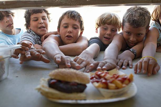children (6-10) at fastfood vendor's window, reaching for plate - junk food stock pictures, royalty-free photos & images