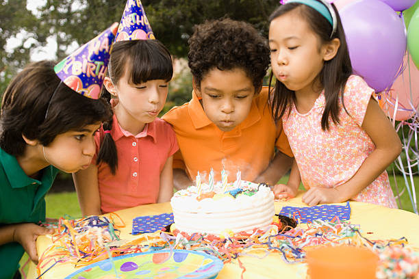 children blowing out candles on birthday cake - garden decoration stock pictures, royalty-free photos & images