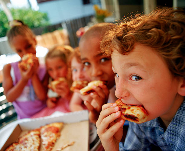 children eating pizza outdoors - junk food stock pictures, royalty-free photos & images