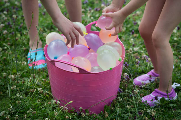 children grabbing water balloons from a bucket - garden decoration stock pictures, royalty-free photos & images