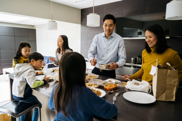 chinese family of four eating takeout food for evening meal - junk food stock pictures, royalty-free photos & images