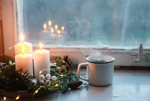 christmas home decorations: white candles and pine branch wreath on vintage wooden window sill, cup of hot coffee. - home decoration stock pictures, royalty-free photos & images