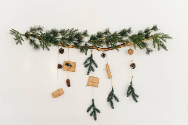 christmas tree branch with a garland and gifts on the wall. new year. christmas. christmas decor. christmas tree. christmas background. holiday. - home decoration stock pictures, royalty-free photos & images