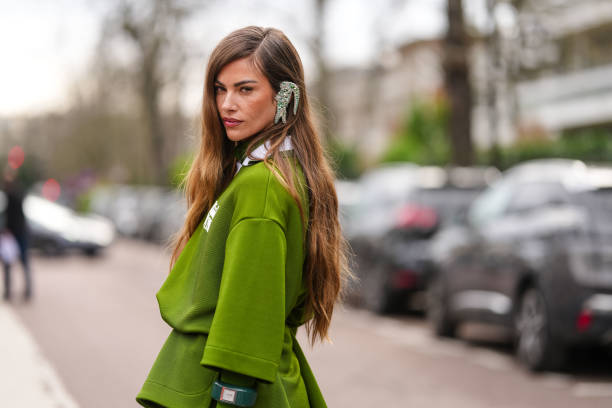 Clara Berry wears silver Lacoste earrings, dark green white oversized short sleeve shirt, dark green long sleeve shirt, outside Lacoste, during the...