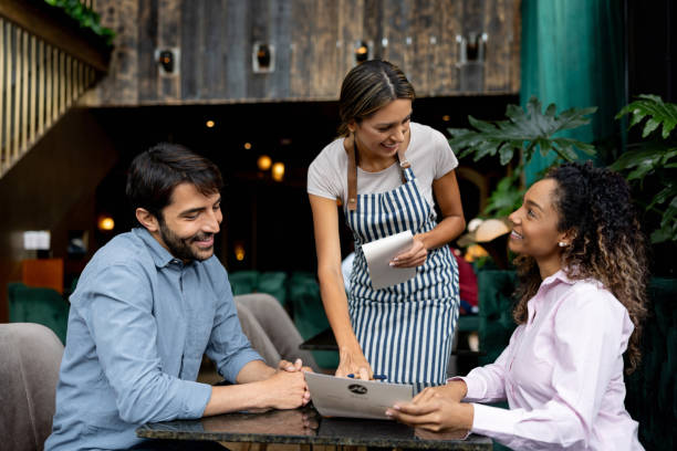 clients at a restaurant asking questions about the menu to the waitress - food stockfoto's en -beelden