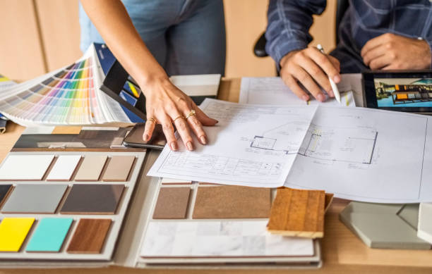 close-up of a architect discussing building blueprints with female colleague in office - home decoration stock pictures, royalty-free photos & images