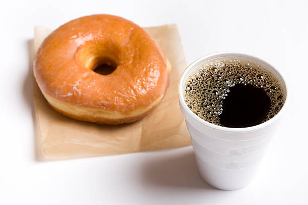 close-up of a cup of black coffee and a glazed donut - junk food stock pictures, royalty-free photos & images