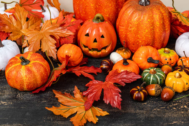 close-up of an autumnal halloween decoration with assorted pumpkins, autumn leaves and a jack-o-lantern - home decoration stock pictures, royalty-free photos & images