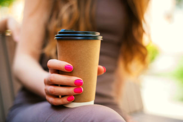 close-up of an unrecognizable young woman holding recyclable takeaway coffee cup in outdoors - junk food stock pictures, royalty-free photos & images