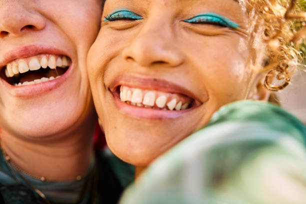 close-up of two gen z adults smiling and laughing outdoors. urban environment. friendship and well-being. - fashion stock pictures, royalty-free photos & images