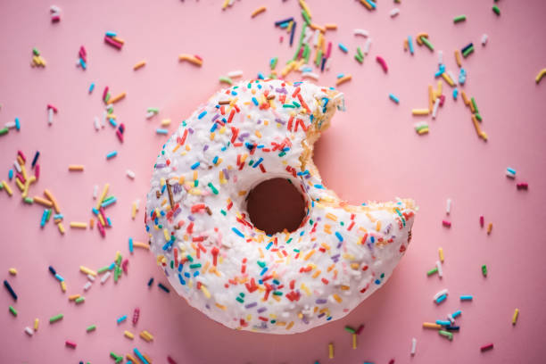 close-up of white donuts with multi colored sparks - junk food stock pictures, royalty-free photos & images