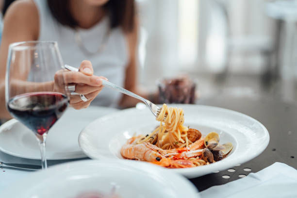 close-up of young woman eating fresh seafood pasta in restaurant - food stock pictures, royalty-free photos & images