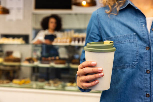 close-up on a customer buying a cup of coffee to go at a cafe - junk food stock pictures, royalty-free photos & images