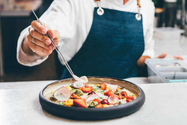 close up a chef preparing a gourmet dish. chef is decorating the plate just before the serving. - food stock pictures, royalty-free photos & images