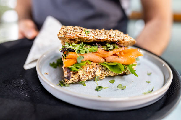 close up from fresh salmon sandwich serving from waiter - junk food stock pictures, royalty-free photos & images