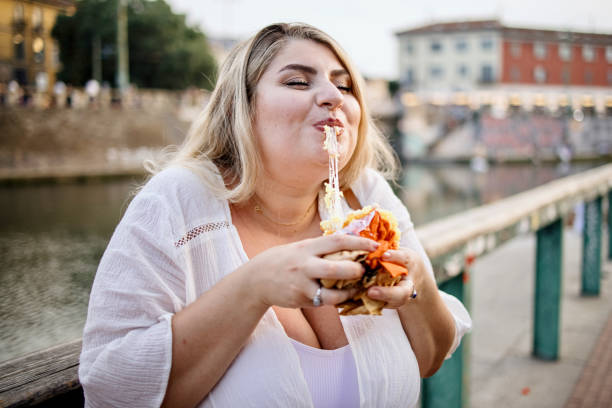 close up of a woman eating and enjoying fast food outside - junk food stock pictures, royalty-free photos & images