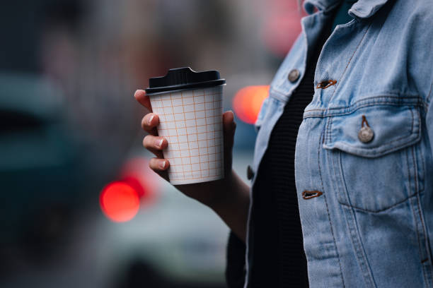 close up of an anonymous woman walking and holding a paper coffee cup - junk food stock pictures, royalty-free photos & images