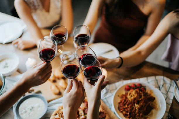 close up of happy young friends having fun and toasting and celebrating with red wine during party - food stock pictures, royalty-free photos & images
