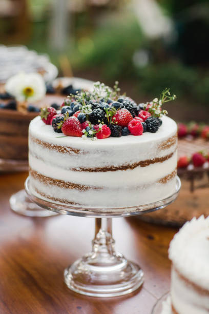 close up of mixed berry white wedding cake dessert display with berries for a smaller wedding celebration in a backyard in summer july - garden decoration stock pictures, royalty-free photos & images