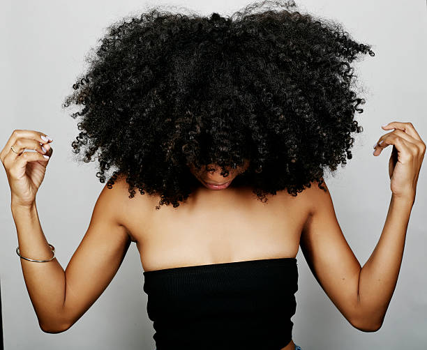 close up of mixed race woman with curly hair looking down - hairstyle fotografías e imágenes de stock