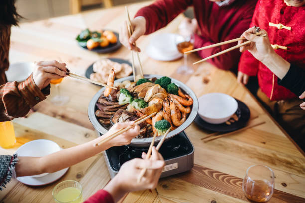 close up of three generations of joyful asian family celebrating chinese new year and enjoying scrumptious traditional chinese poon choi on reunion dinner - food stock pictures, royalty-free photos & images