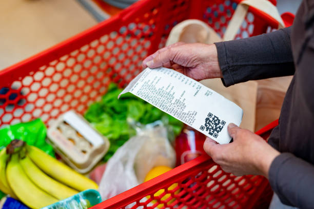 close up of unrecognizable customer checking her receipt after purchasing groceries in the supermarket - food stockfoto's en -beelden