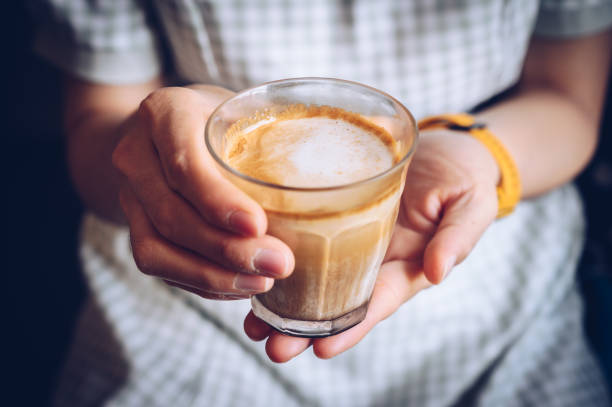 close up of woman hand holding a cup of dirty latte before drink it. - coffee stock pictures, royalty-free photos & images