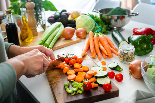 close up of woman's hands slicing fresh organic carrots on kitchen counter - food stock pictures, royalty-free photos & images