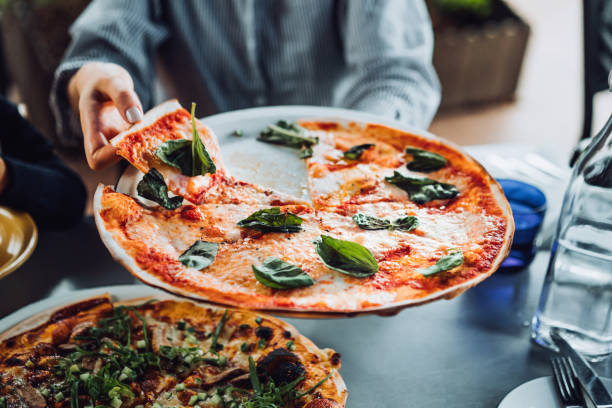 close up of young asian woman getting a slice of freshly made pizza. enjoying her meal in an outdoor restaurant. italian cuisine and culture. eating out lifestyle - junk food stock pictures, royalty-free photos & images