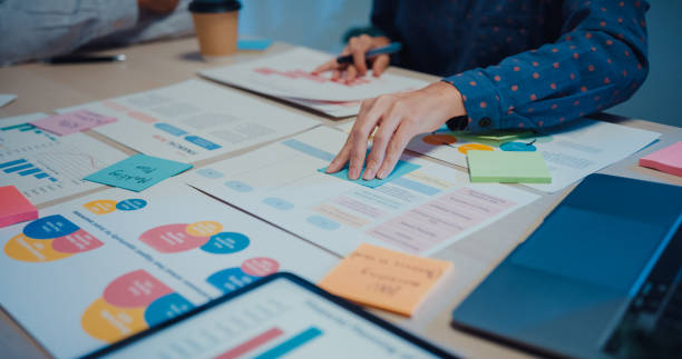close up of young businesspeople meeting about new project with colleagues in conference room at night office. - fashion stock pictures, royalty-free photos & images