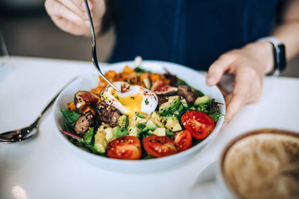 close up shot of a woman eating a dish of fresh beef cobb salad with a soft boiled egg and coffee at a cafe table. enjoying her healthy and nutritious lunch. maintaining a healthy and well-balanced diet. the concept of health