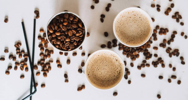 coffee to go in tray on white table with coffee beans and straws - junk food stock pictures, royalty-free photos & images