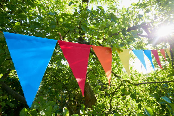 colorful bunting flags/ pennant chant at an apple tree for party decoration in garden - garden decoration stock pictures, royalty-free photos & images
