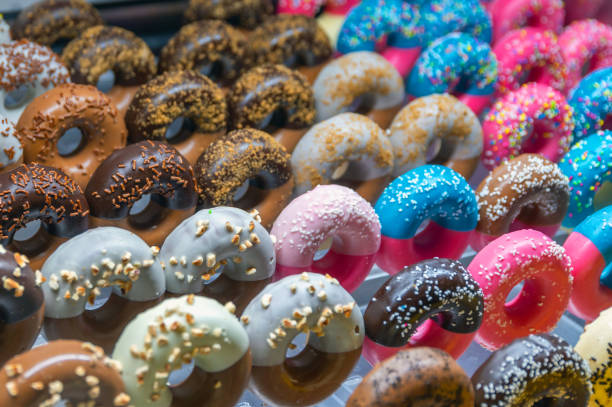 colorful donuts on display - junk food stock pictures, royalty-free photos & images