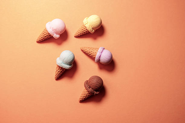 colorful ice cream cones lying on orange background - junk food stock pictures, royalty-free photos & images