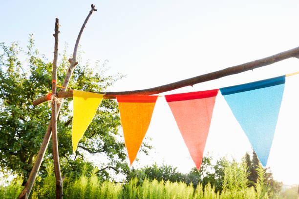 colourful bunting flags/ pennant chain for party decoration in a garden against sky - garden decoration stock pictures, royalty-free photos & images