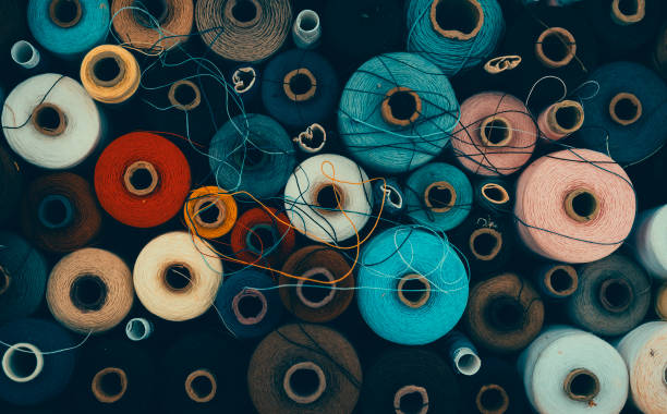 composition of sewing spools with colorful vibrant threads from above - fashion stock pictures, royalty-free photos & images