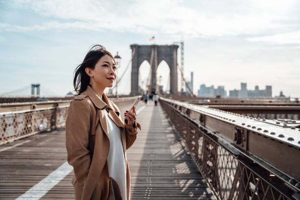 confident businesswoman using smart phone on brooklyn bridge, new york - travel stock pictures, royalty-free photos & images