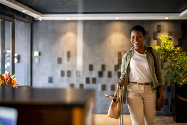 confident young woman arriving in hotel reception - travel stock pictures, royalty-free photos & images
