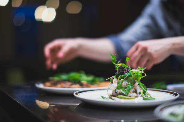 cook preparing many plates in a restaurant kitchen. catering. caterer - food stock pictures, royalty-free photos & images