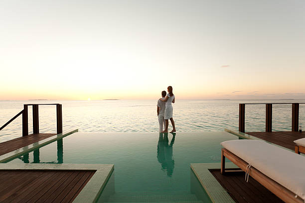 couple admirant le coucher du soleil au bord de la piscine - travel photos et images de collection