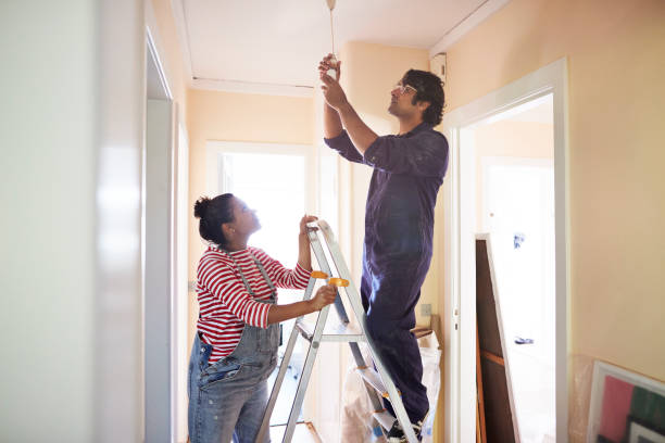 couple changing light bulb in corridor - home decoration stock pictures, royalty-free photos & images