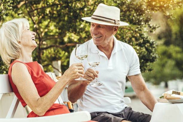 couple de personnes âgées portant un toast avec du vin et célébrant leur anniversaire - garden decoration photos et images de collection