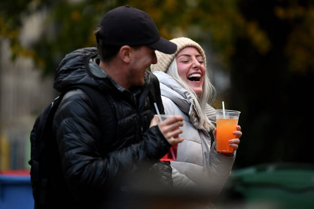 Couple drink from takeaway glasses outside a pub in the Grassmarket following last orders at 6pm on October 9, 2020 in Edinburgh, Scotland. Pubs and...
